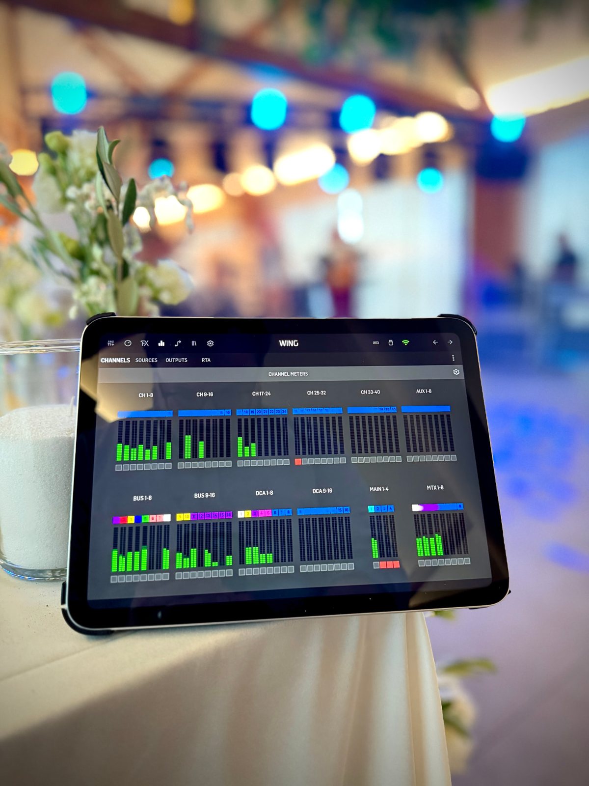 Tablet remote for a WING console at an event with stage lights behind